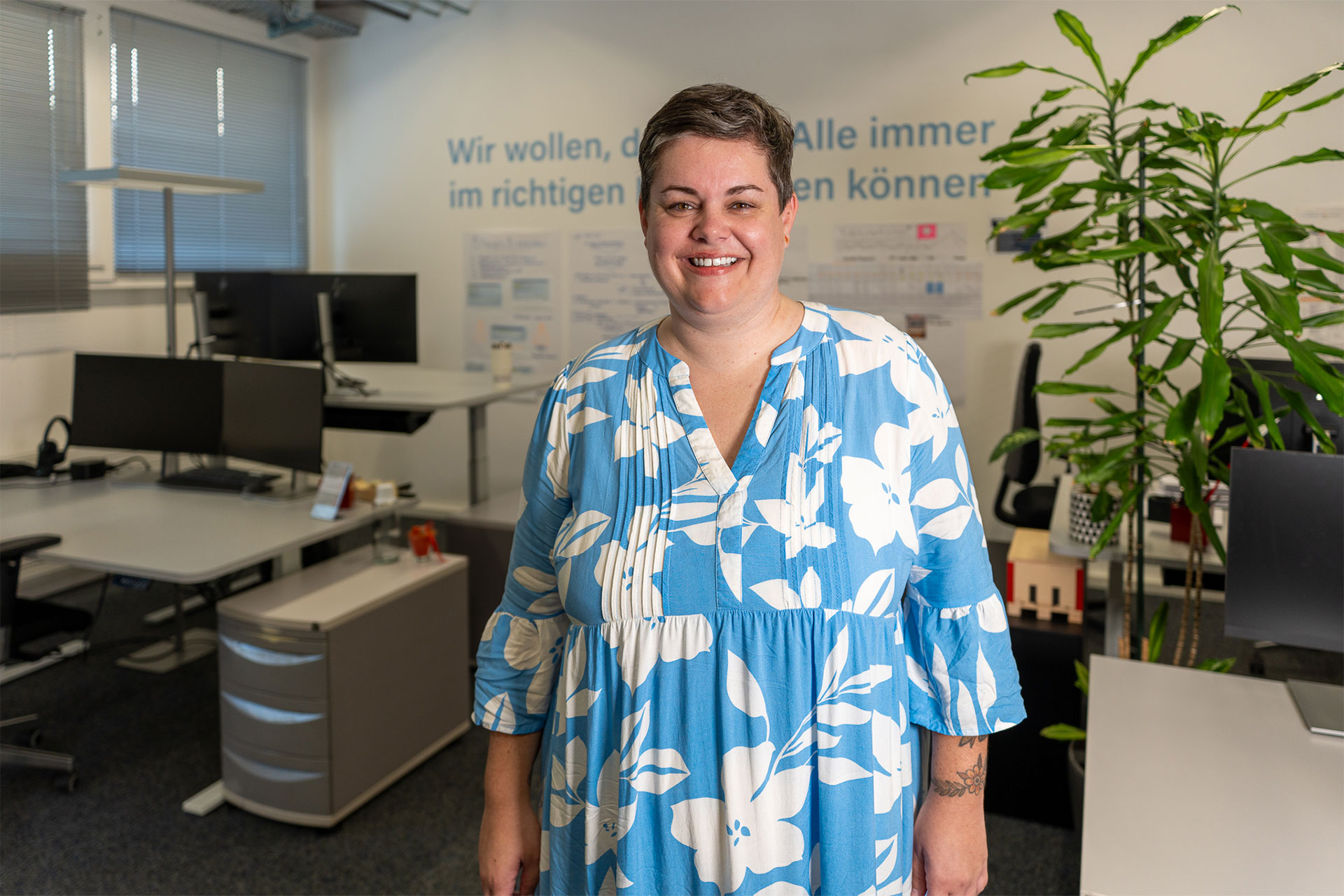 Portrait von Martina Mächler, Leiterin Innendienst bei W. Schneider, lächelnd in einem modernen Büro vor einer Wand mit dem Unternehmensslogan.