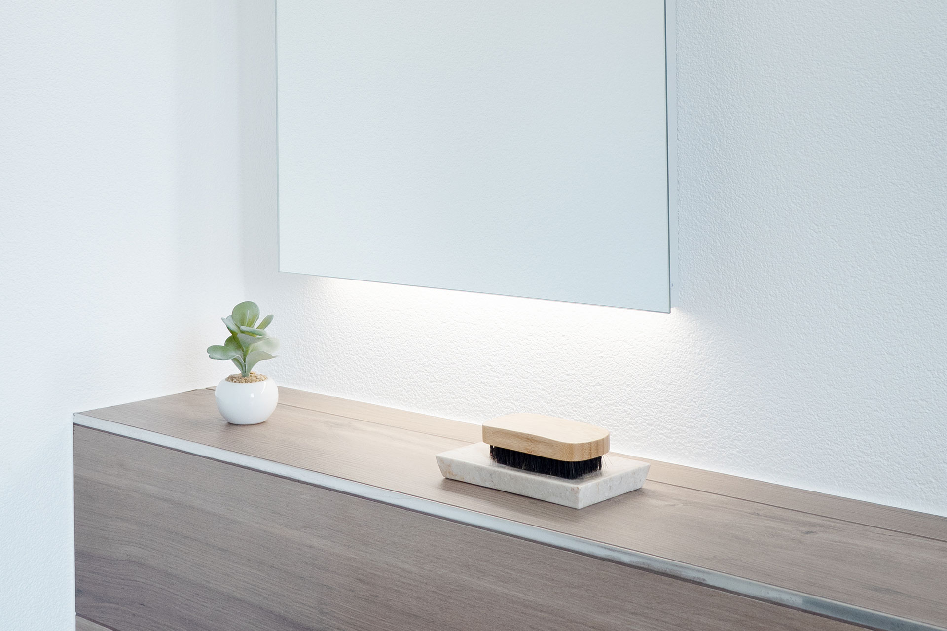 Der Lichtspiegel ARANGA Line leuchtet indirekt nach unten auf Pflegeprodukte.