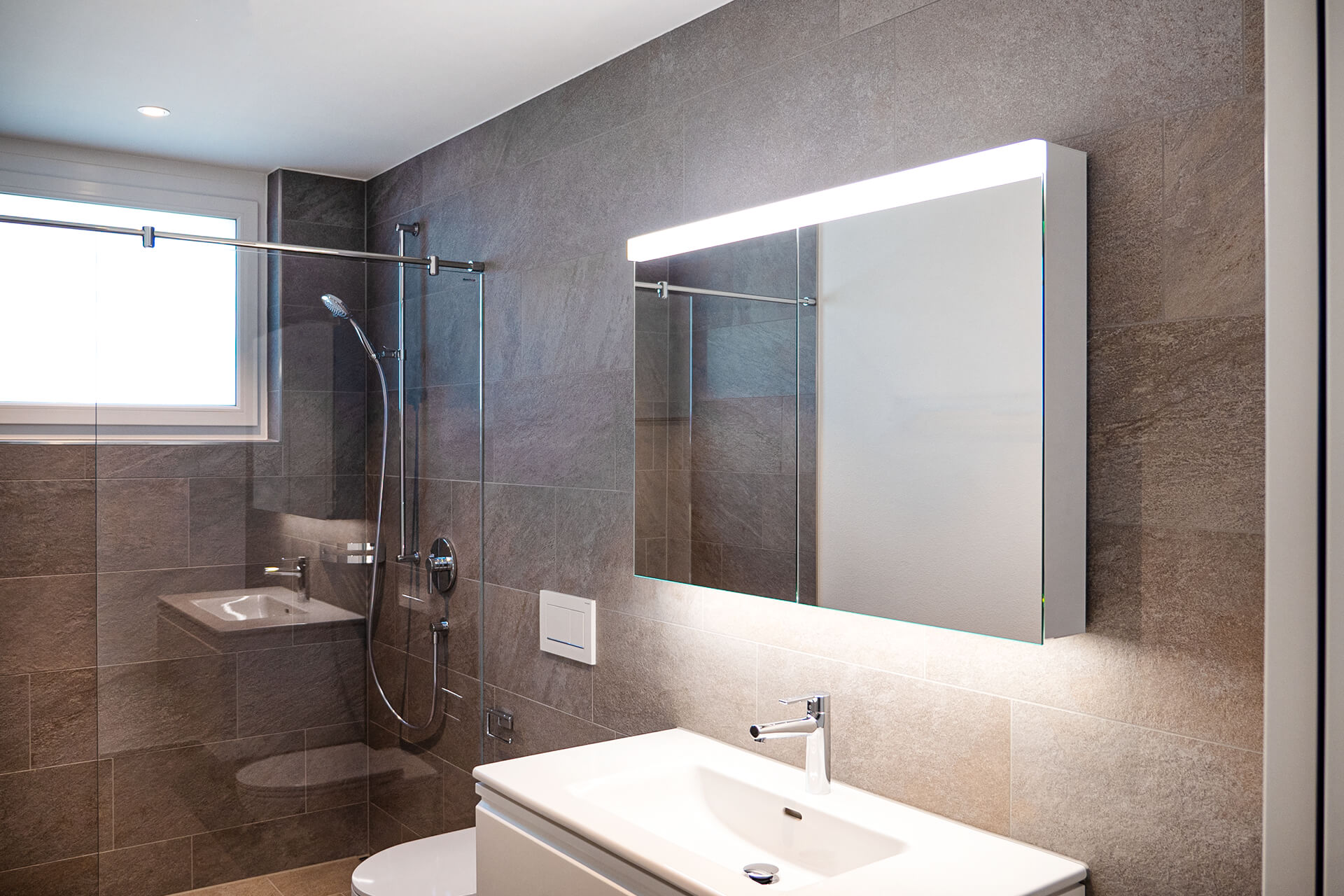 Armadio a specchio a LED LOW Line PLUS montato a parete. Doccia, WC e lavabo.