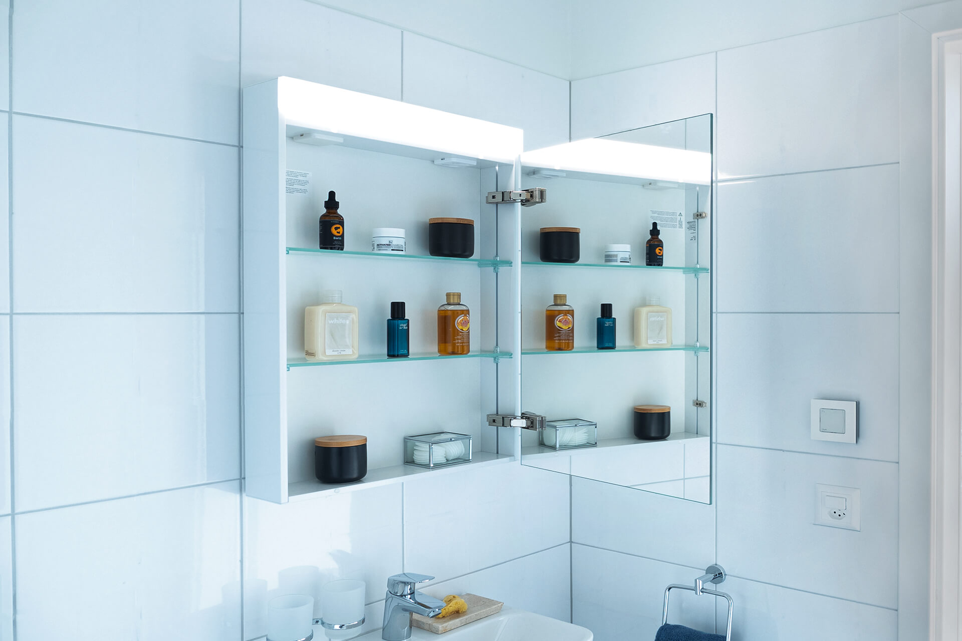 Armoire de toilette PATA Line LED - diffuse une lumière LED de première qualité en blanc neutre (4000 K) ou en blanc chaud (3000 K). Armoire de toilette PATA Line LED sur paroi en plaques de céramique. Avec fenêtre à droite. Plan de toilette.