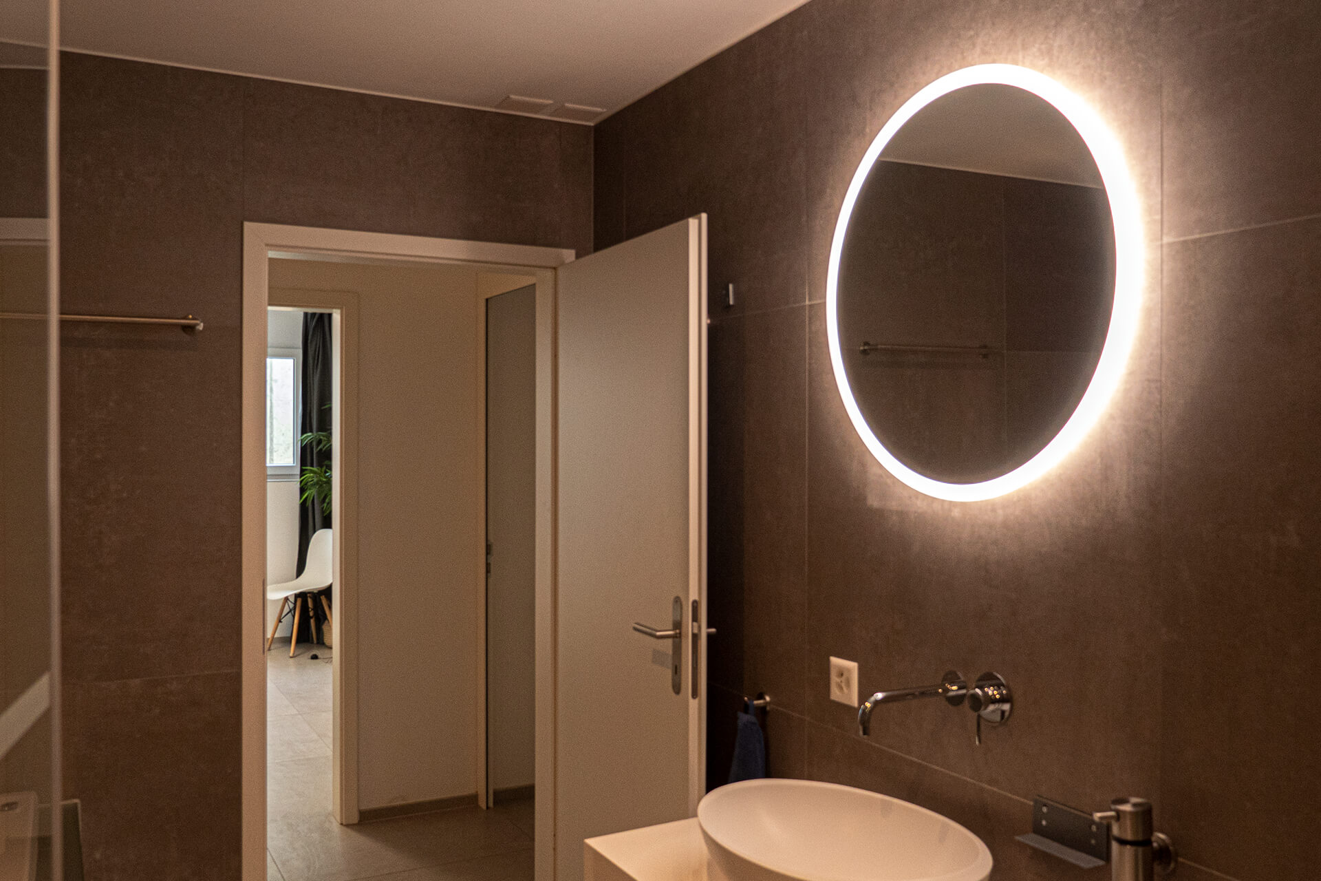 Round mirror with backlighting door and washbasin.