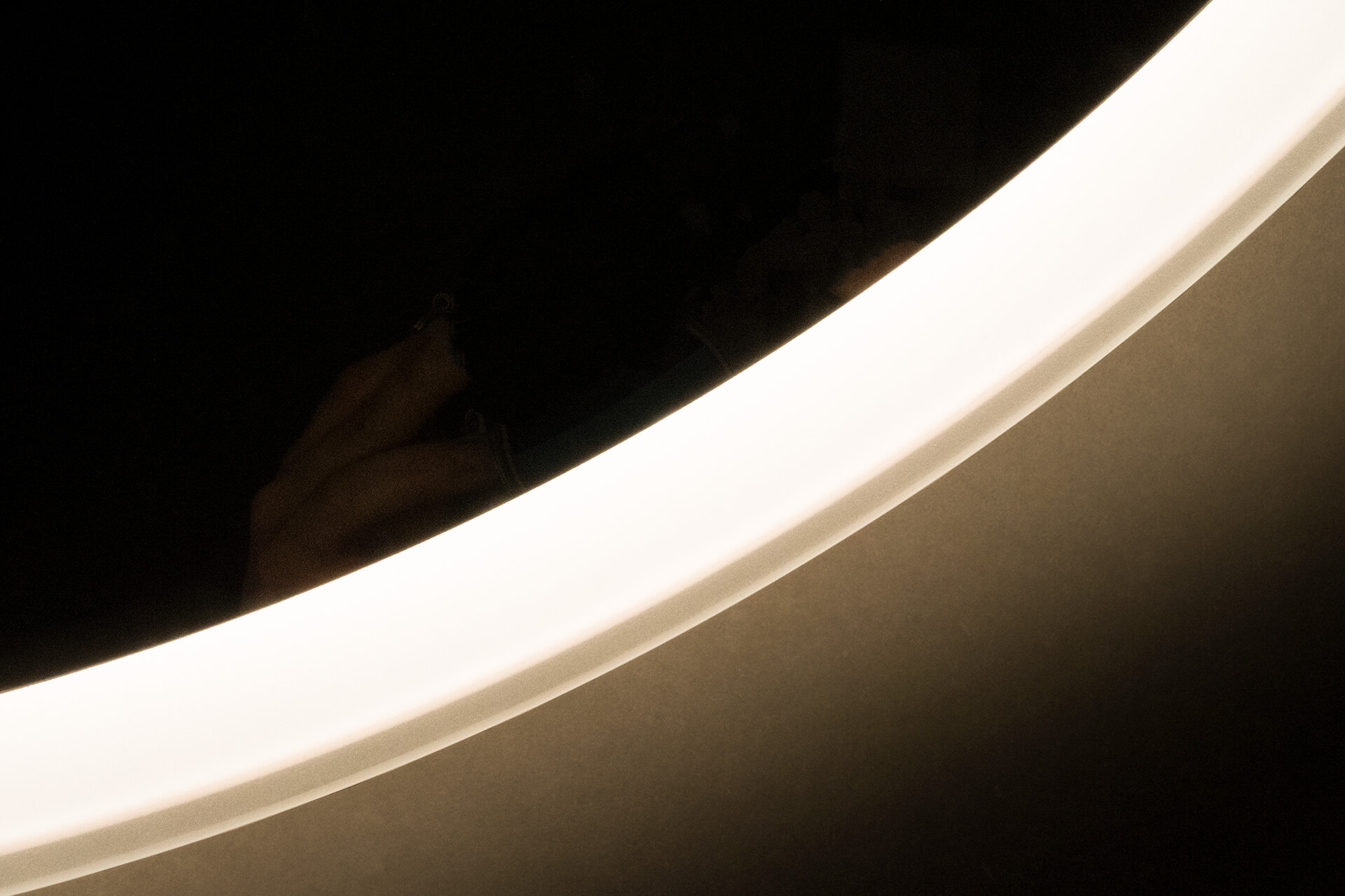 Round mirror with backlight detail below frame.